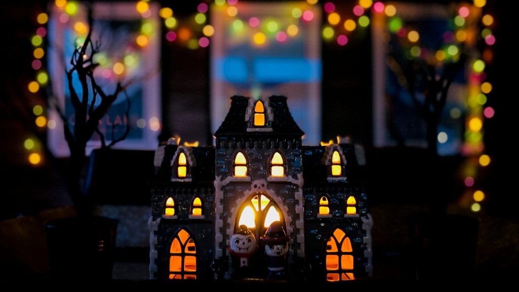 Illuminated miniature haunted house with colourful lights in the background
