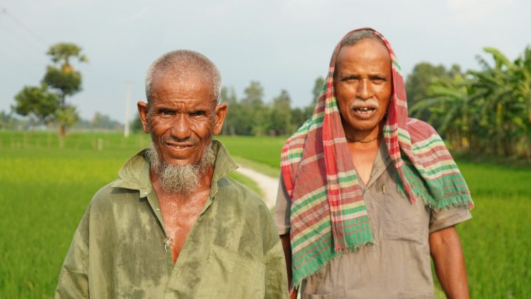 Two farmers standing in a green agricultural field