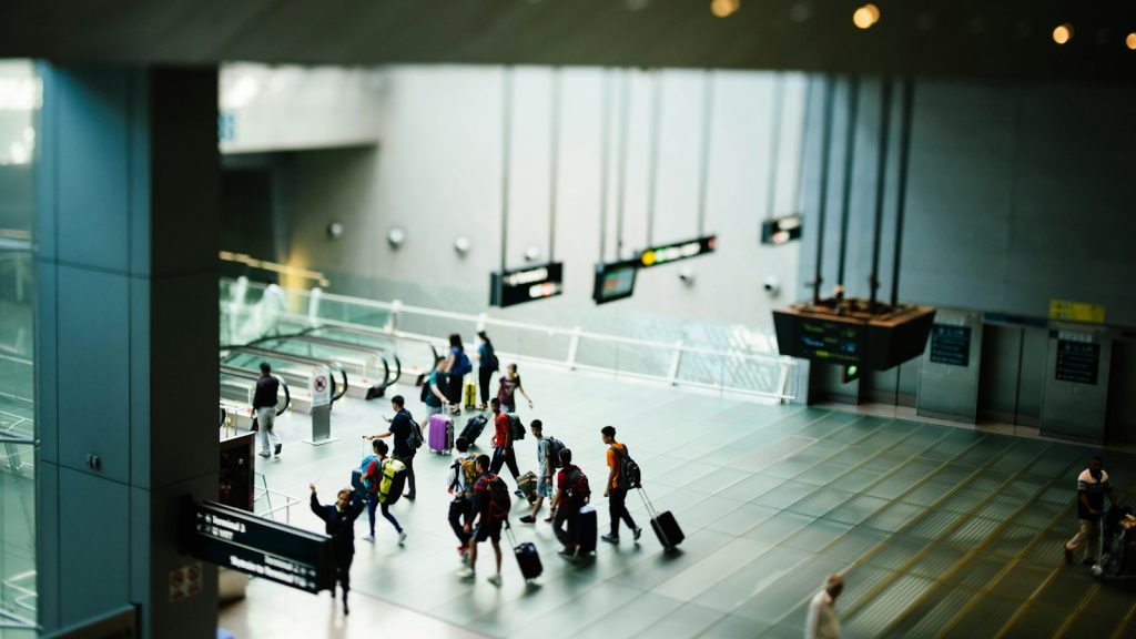 Travellers pulling luggage through a large airport terminal