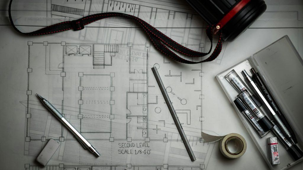 Architectural plans with drafting pencils and measuring tools