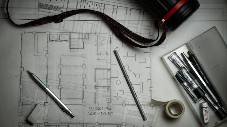 Architectural plans with drafting pencils and measuring tools