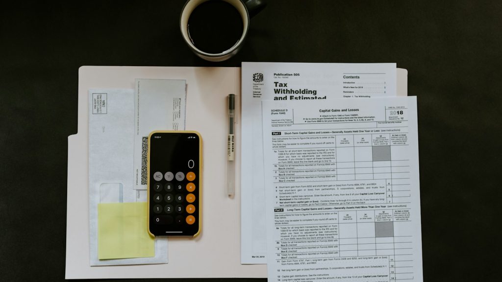 Calculator, paperwork, pen and coffee arranged on a desk
