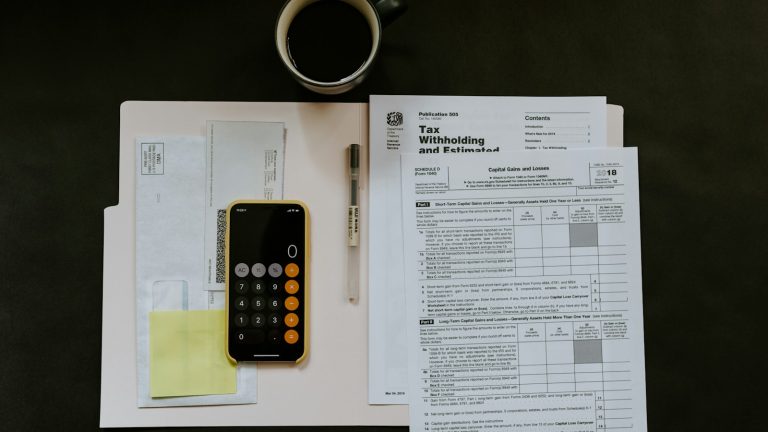 Calculator, paperwork, pen and coffee arranged on a desk