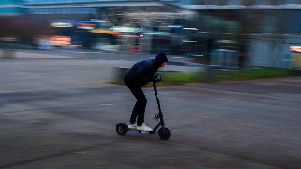 Person riding an electric kick scooter in an urban area