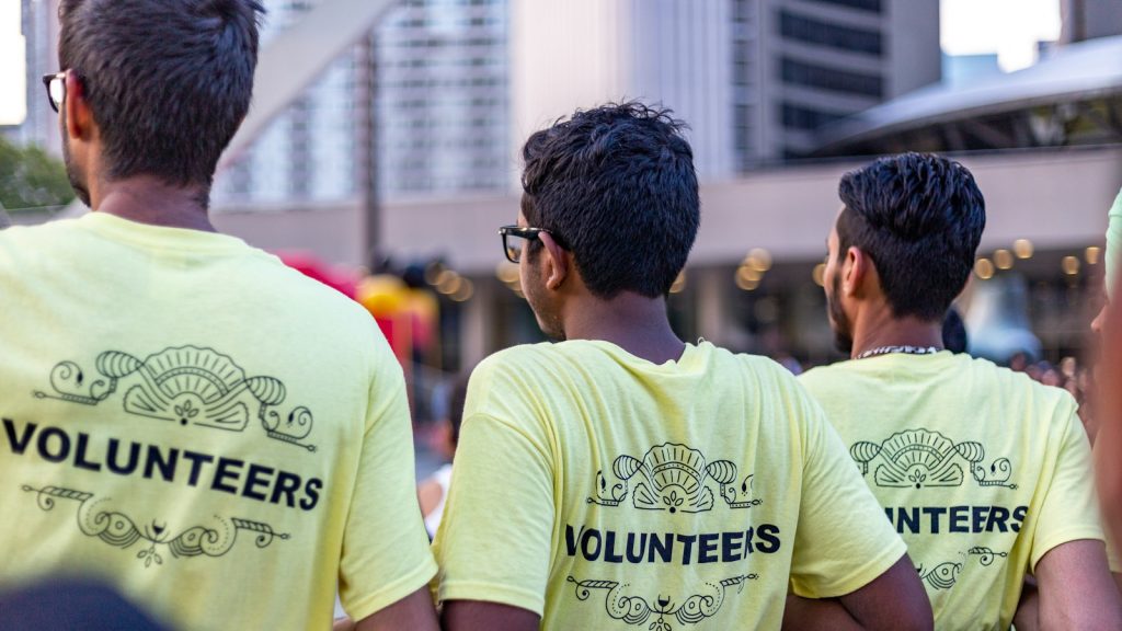 Three people wearing yellow volunteer shirts at an outdoor event