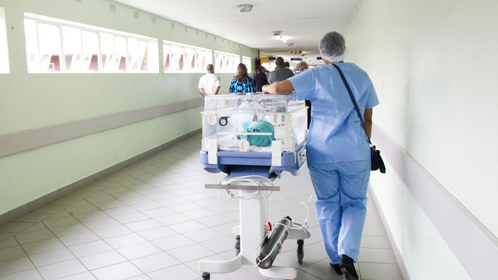 Health-care worker moving equipment through a hospital corridor