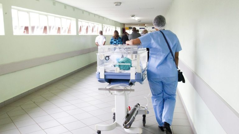 Health-care worker moving equipment through a hospital corridor