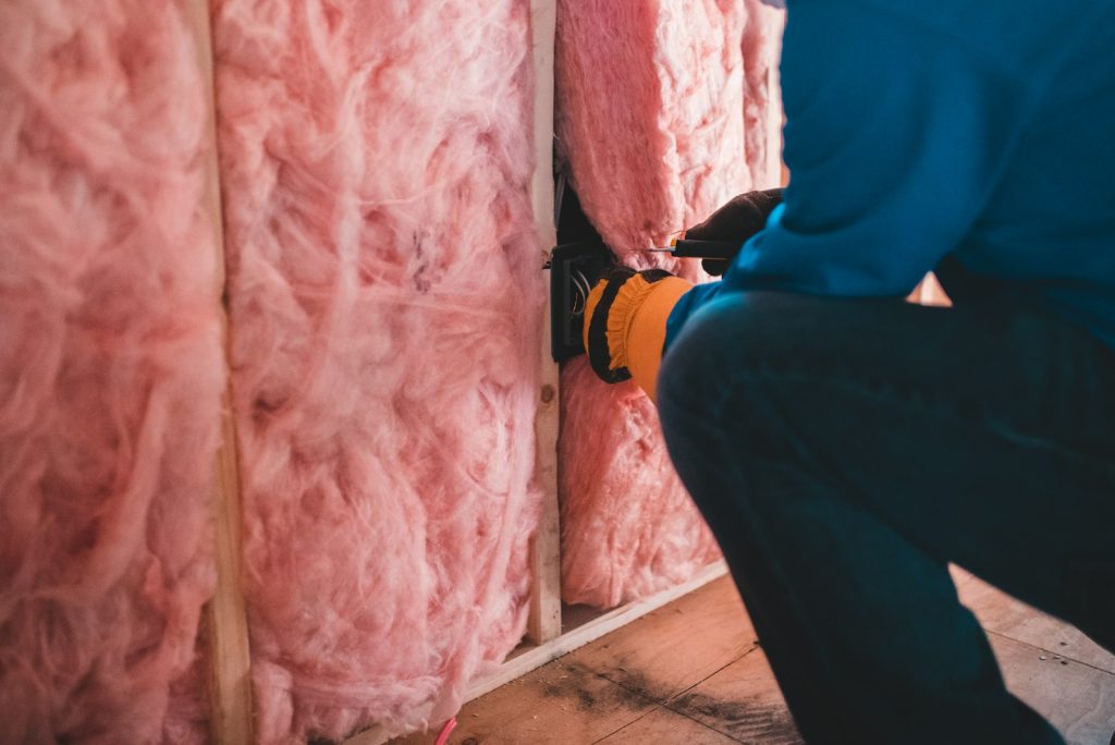 Worker installing wiring beside wall insulation during a home renovation