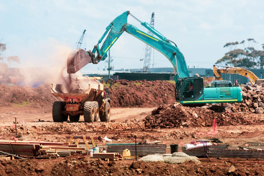 Excavator loading earth into a dump truck at a construction site