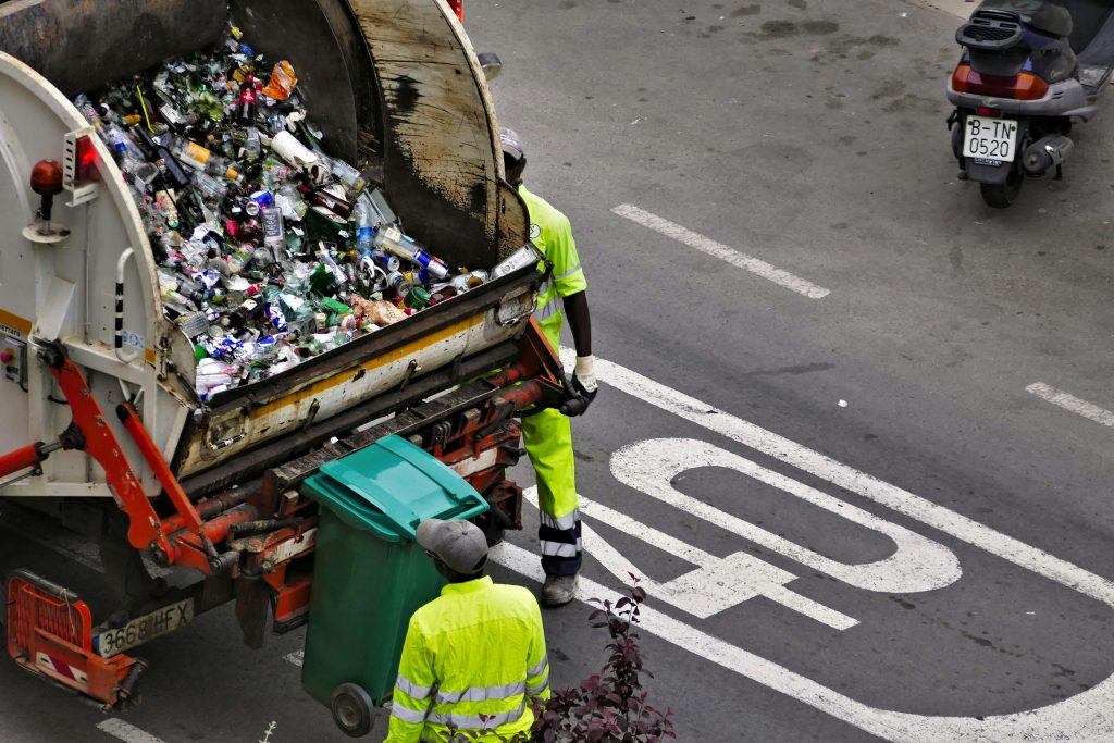 Waste collection workers beside a truck and recycling containers