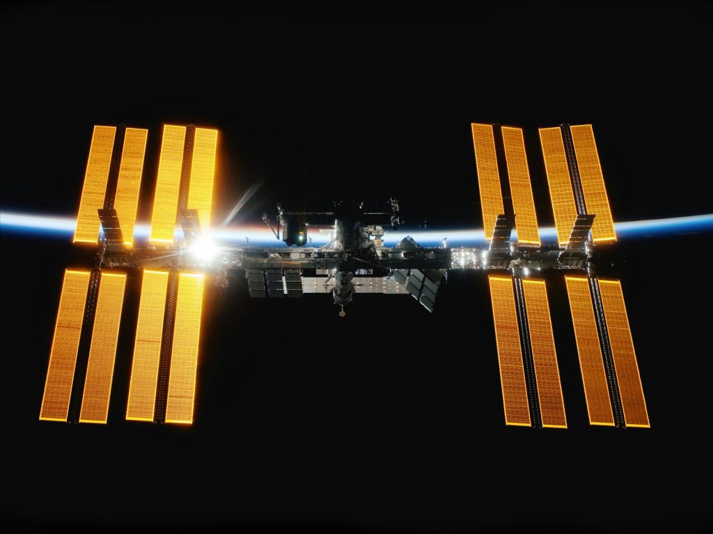 International Space Station above Earth with illuminated solar arrays, file photo.