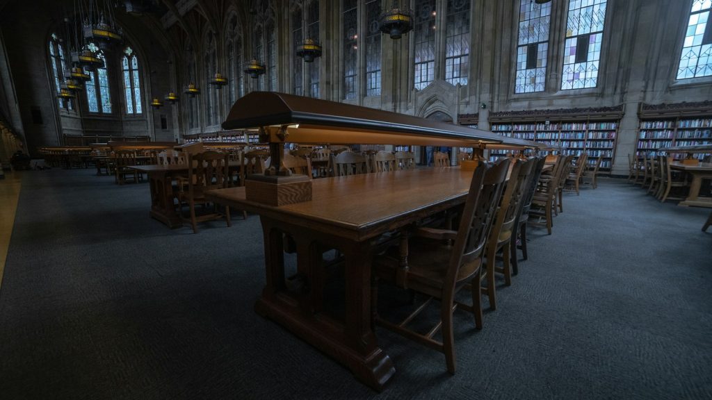 An empty library reading room with long wooden tables and chairs.