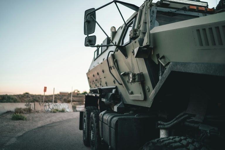 Military transport vehicle travelling on a road, illustrative stock image