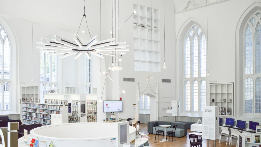 A bright modern library interior with tall arched windows and bookshelves.