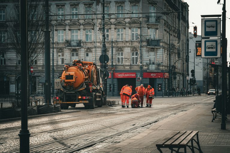 Municipal public works crew in orange safety clothing beside a maintenance truck