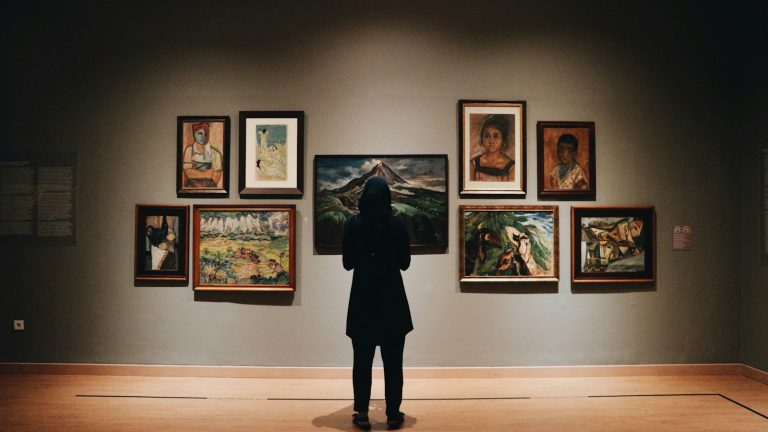 Visitor viewing framed artworks in a museum gallery, illustrating museum attendance
