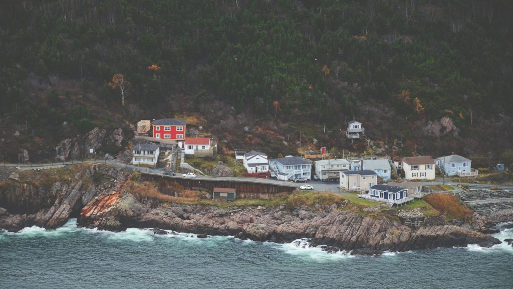 Homes in a small Newfoundland coastal community beside rocky shoreline