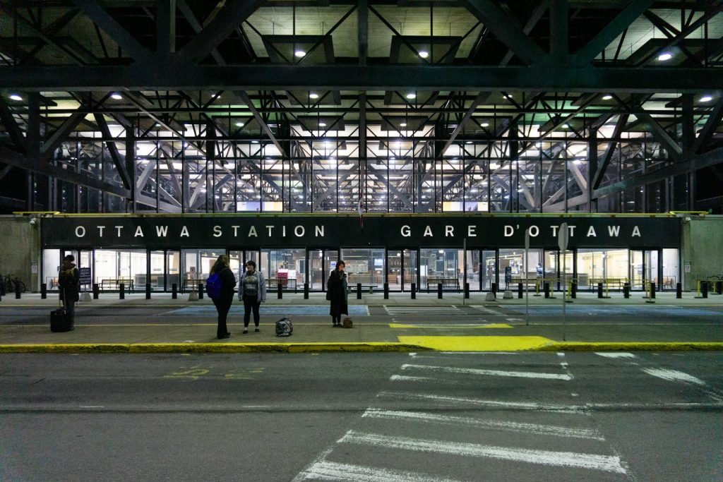 Exterior of Ottawa train station at night with travellers near the entrance