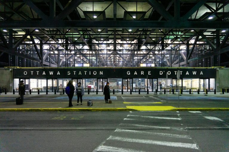 Exterior of Ottawa train station at night with travellers near the entrance