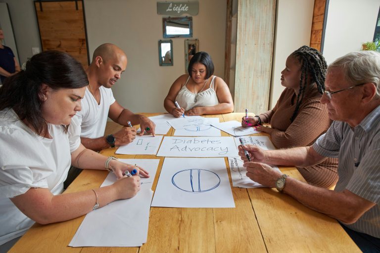 People drawing on paper around a table, illustrative image for a planning committee