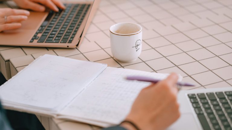 People working together with laptops, notes and coffee at a table