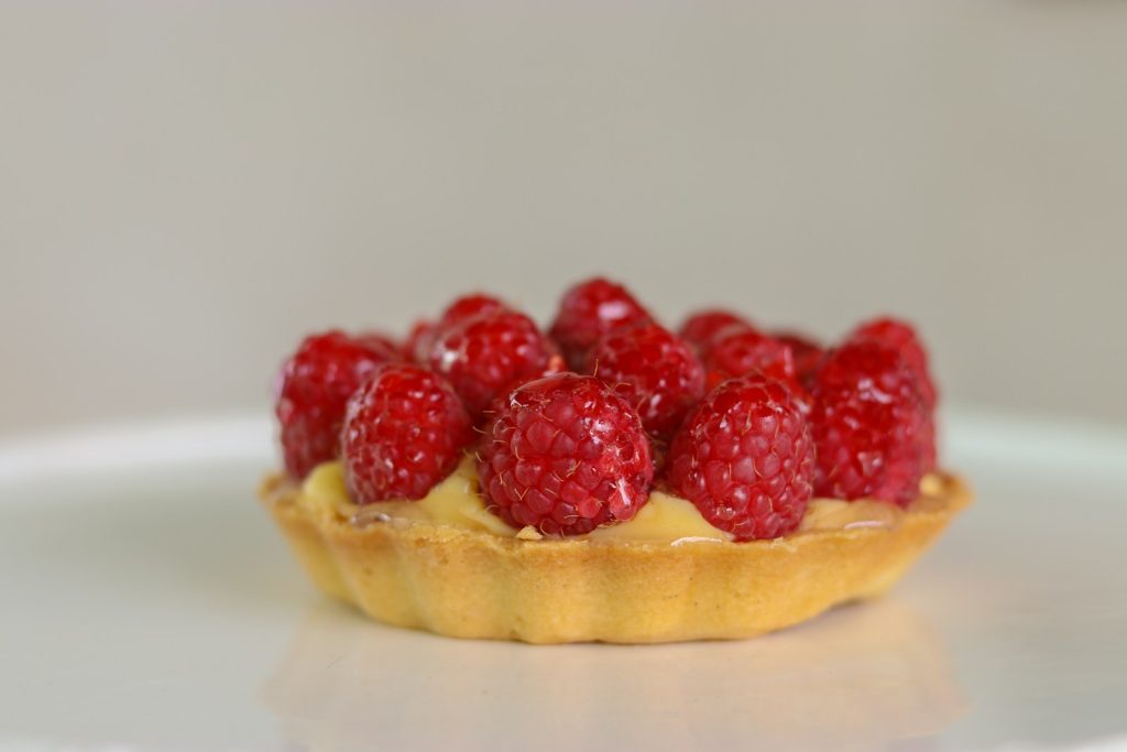 Raspberry and custard tart topped with fresh raspberries