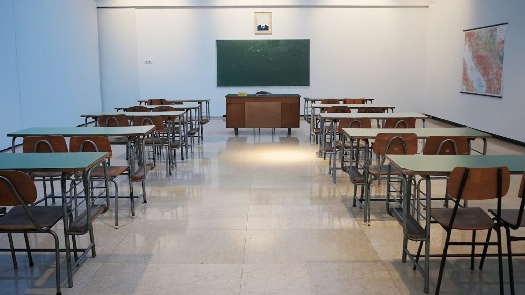 An empty classroom with desks facing a chalkboard
