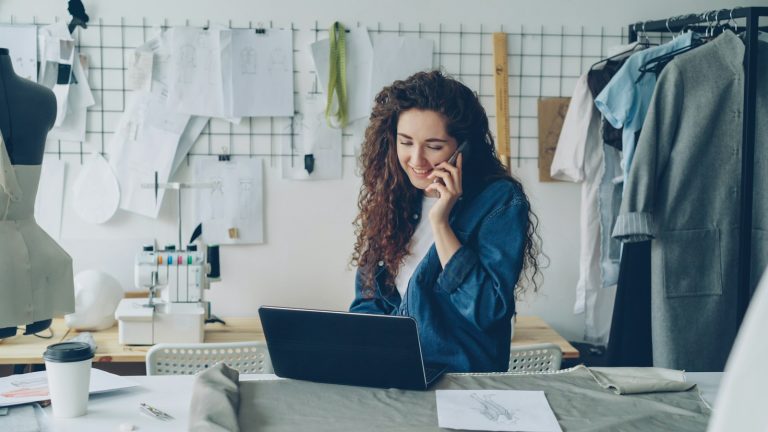 A small-business owner working at a laptop in a tailoring studio