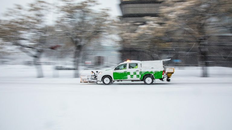 Snowplow driving through heavy snow on a city street