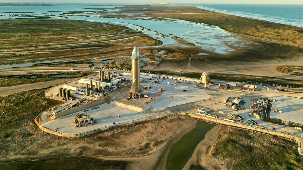 Aerial view of rockets and launch infrastructure at a coastal launch site