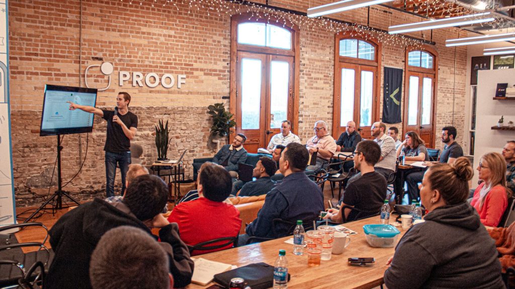 A presenter speaking to an audience in a startup office