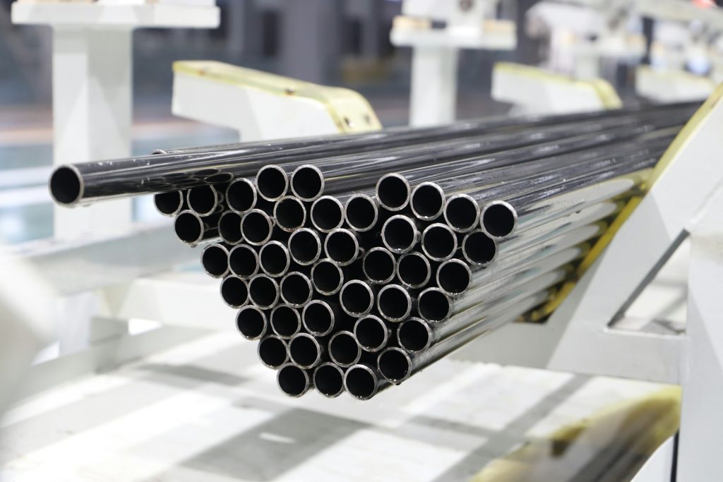 Stack of metal pipes on a factory line, illustrating oil-country tubular goods