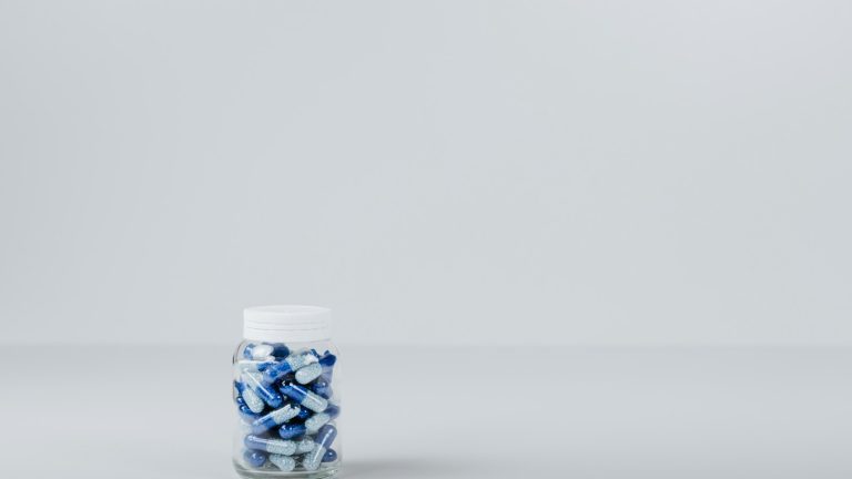 Unlabelled bottle containing blue and white capsules, illustrating the supplements business
