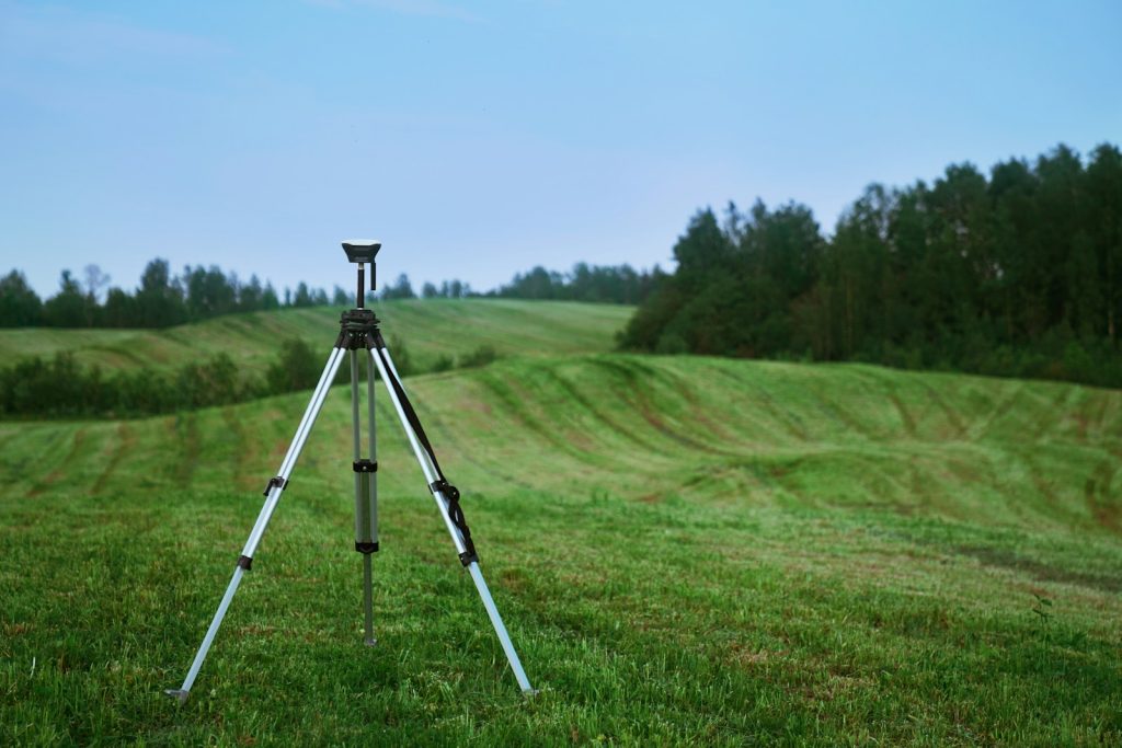 Surveying and positioning equipment set up in a field, illustrative stock image