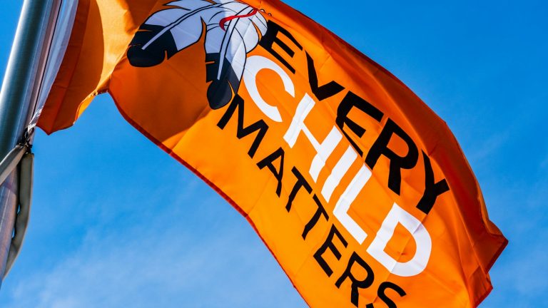 Orange Survivors’ Flag flying against a blue sky