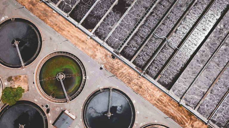 An aerial view of circular tanks and filtration basins at a water treatment facility.