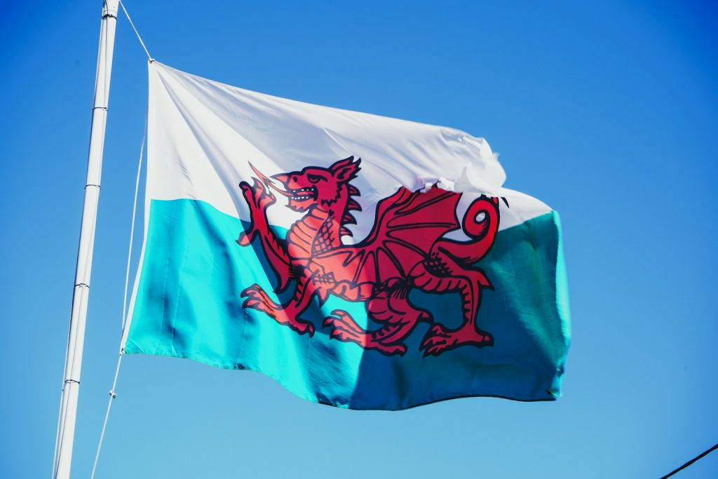 Red dragon of Wales on a white and green flag against a blue sky