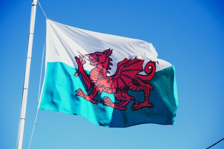 Red dragon of Wales on a white and green flag against a blue sky