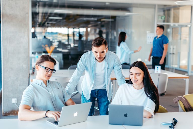 Young professionals collaborating at laptops in an office, used to illustrate Canada Summer Jobs